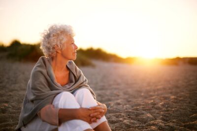 An old women on the beach looking into the distance